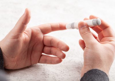 man hands using lancet on finger to check blood sugar or ketones level by glucose meter. medicine diabetes keto diet health care at home