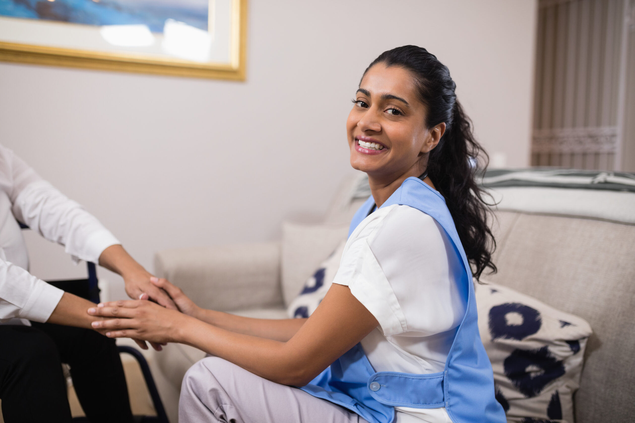Portrait of smiling young doctor touching patient hands at home